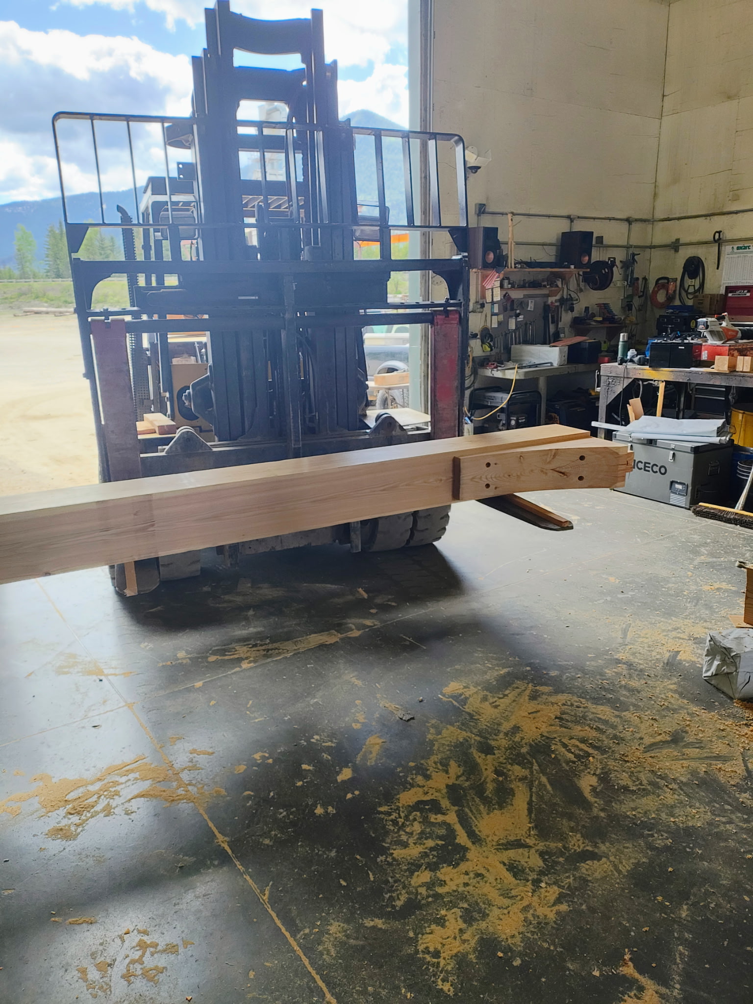 Forklift handling a finished heavy timber beam in the workshop